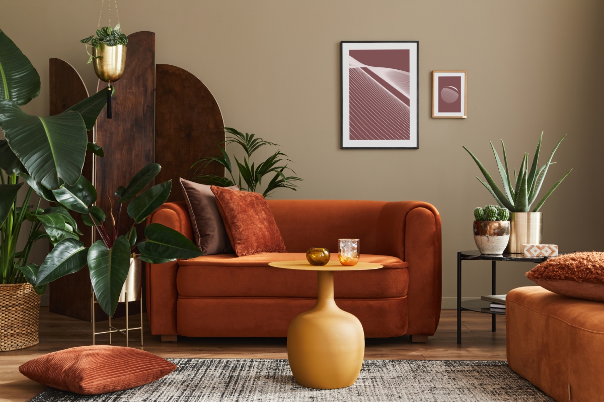 Salon contemporain au canapé orange et plantes vertes, illustrant un bien à louer.