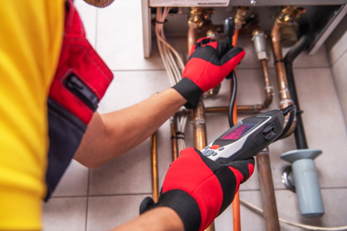 Technicien inspectant une chaudière gaz avec un appareil de diagnostic numérique.