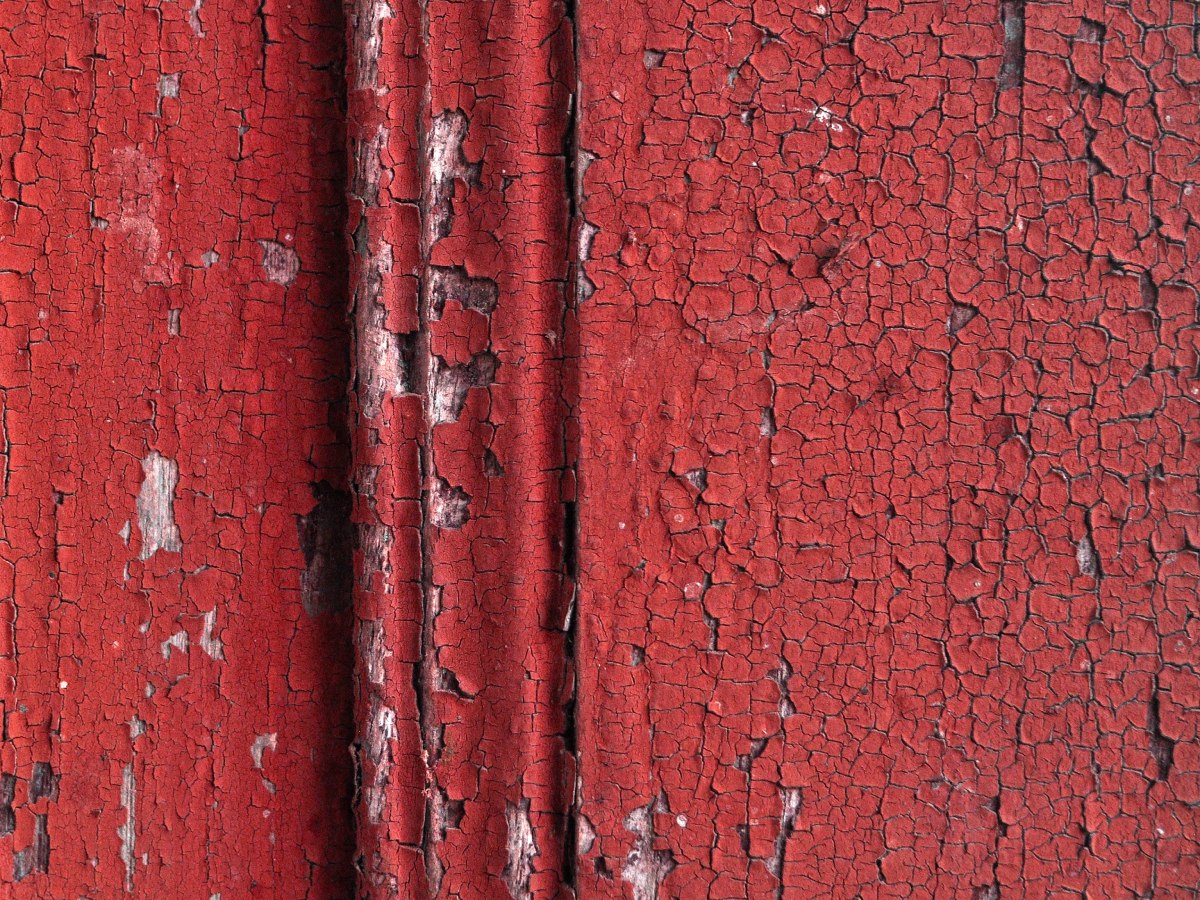 Peinture rouge écaillée sur bois, signe typique d'un diagnostic plomb à réaliser.